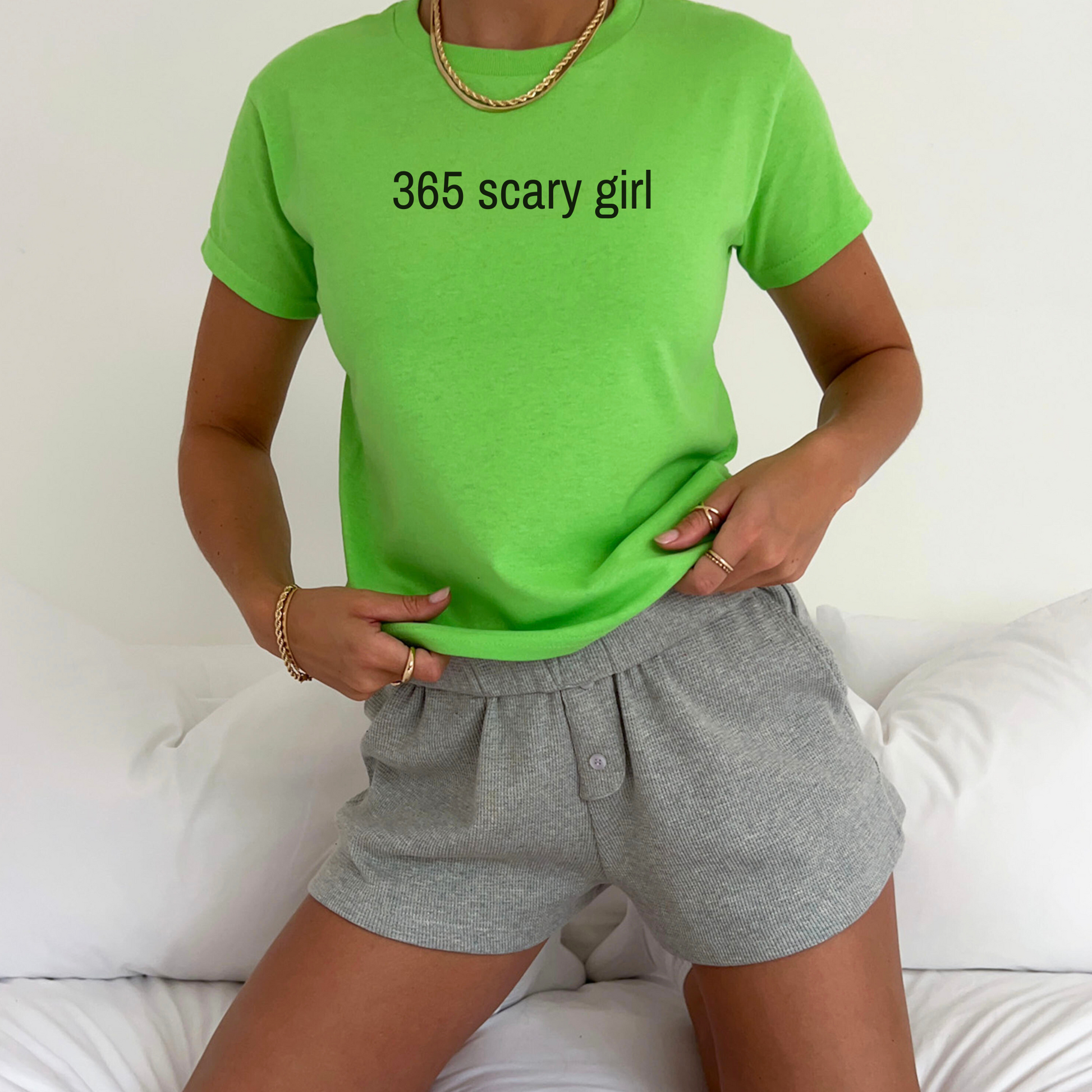 Person wearing a bright green t-shirt with '365 scary girl' text and gray shorts on a white background.